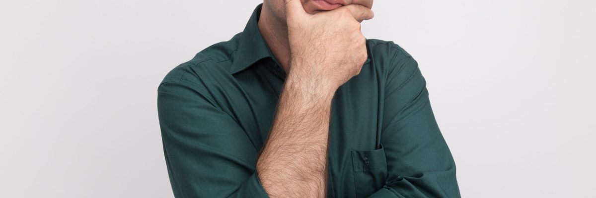 thinking middle-aged man wearing green t-shirt grabbed chin isolated on white background